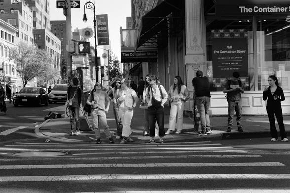 A group of people waiting to cross a city street