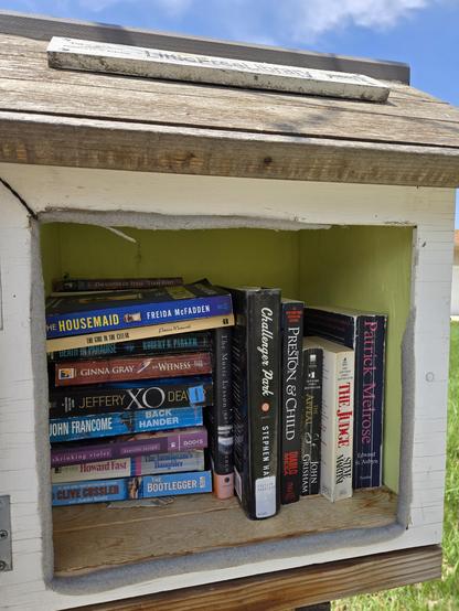 A little free library full of free books. A blue sky and clouds can be seen in the background.