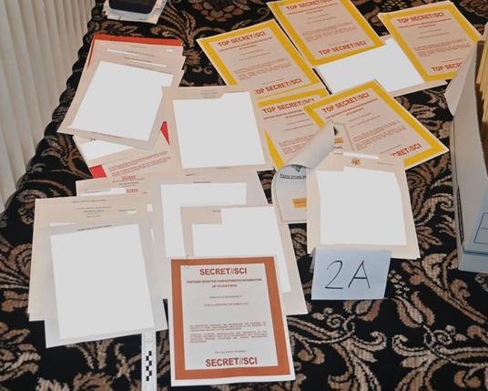 A collection of documents labeled 'Top Secret' and 'Secret,' partially obscured, spread out on a patterned surface.