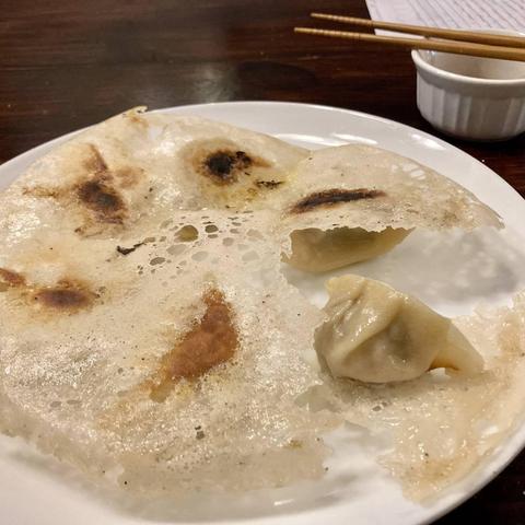 A photo of a plate of turned over “dumpwings”. One dumpling is turned right side up. The rest show a connected layer of starch.