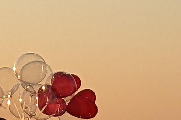 Heart shaped balloons seen against a pastel sunset sky