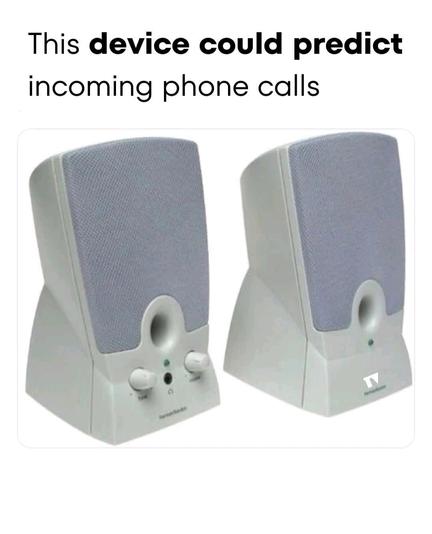 The image features two identical computer speakers positioned side by side against a white background. The speakers are primarily white with gray fabric grills on the front. Each speaker has a circular port at the bottom center, flanked by two white knobs, likely for volume and bass control. Below the knobs, there is a small green LED indicator light. Above the speakers, there is text in black font that reads, "This device could predict incoming phone calls."