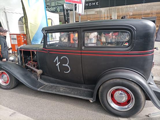 Ein schwarzer Oldtimer mit außen liegendem Trittbrett, wie man es aus amerikanischen Gangsterfilmen kennt am Kudamm