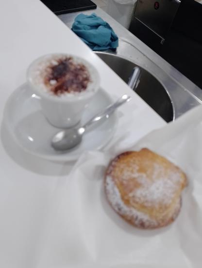 Caffè macchiato caldo solo schiuma e spolverata di cacao e pasticcino tipico palermitano ripieno di crema gialla o ricotta in pasta frolla, chiamato genovese.
