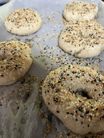 Up close photo of 3 raw bagels with everything seasoning on top of them