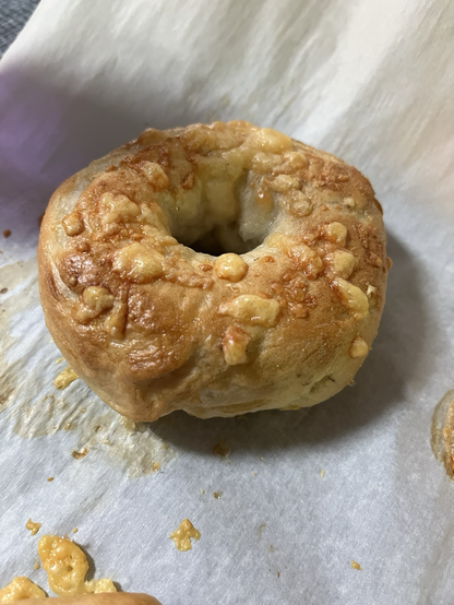 Up close photo of one fresh baked Parmesan topped bagel