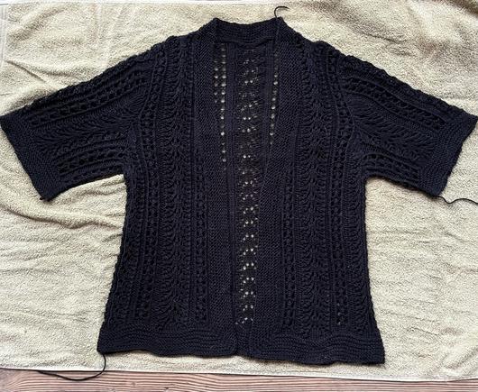 Black lacy short sleeved sweater blocking on a light green towel. Ends have not been woven in.