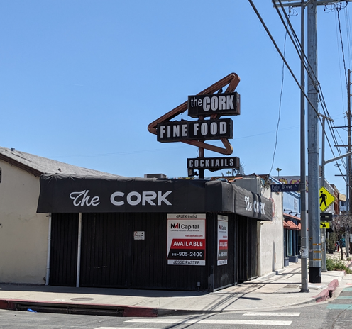 The Cork with a for lease sign on the website and a big googy like sign above it