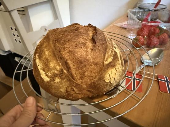 A loaf of bread resting on a circular grill. A little Norwegian flag on a toothpick is seen below the rack