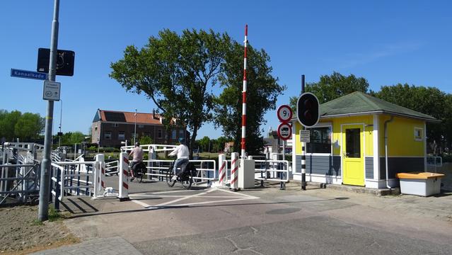 Twee fietsers passeren een vlotbrug met een brugwachtershuis.
