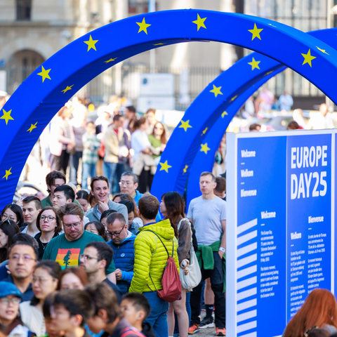Photo of a crowd queuing under blue arches with yellow stars.