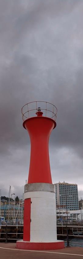 Red city lighthouse against a gray sky.