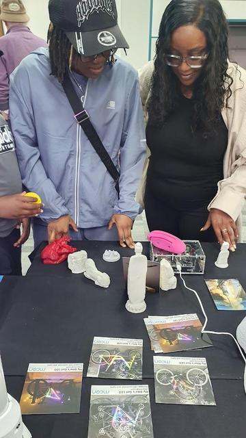 Two young women place a 3D printed object onto Museum in a Box at Wirral Makefest.