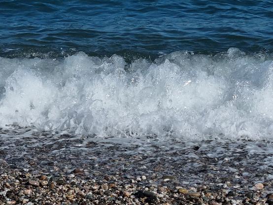 Una onda si alza e schiumeggia sulla riva