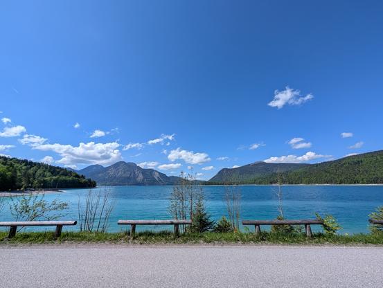 Mautstraße am Südufer vom Walchensee Richtung Jachenau. Blick direkt auf den azurblauen See. Blauer Himmel mit ein paar Wolken.