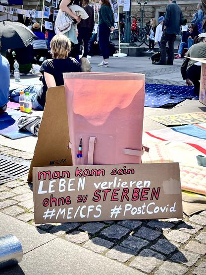 Demo-Schild mit der Aufschrift „man kann sein Leben verlieren, ohne zu sterben #mecfs #postcovid“