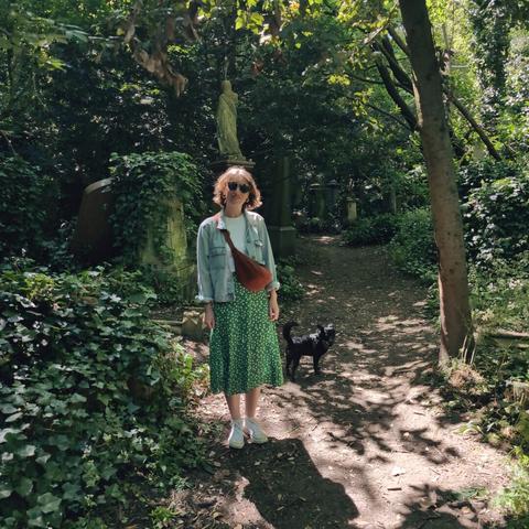 Woman and a small black dog standing in a path in Abney Park cemetery