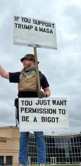guy holding up a double protest sign that says 'if you support trump & maga, you just want permission to be a bigot'