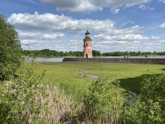 Der Leuchtturm von Moritzburg auf seiner Mole. Es ist Niedrigwasser. Vom See ist nicht viel zu sehen. Vor der Mole wächst schon Gras.