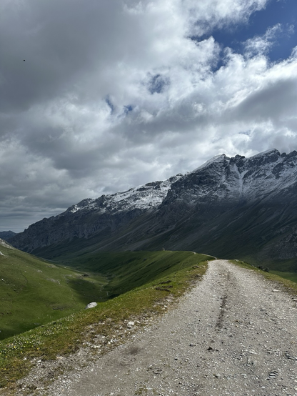 A view of a trail through a snow capped mountain pass