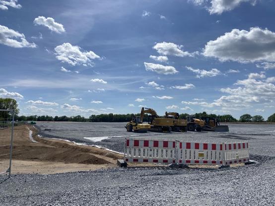 Andere Ansicht der Fläche. Im Vordergrund Baumaschinen und ein Absperrzaun.