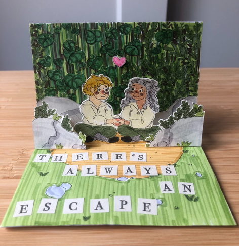 Image description by Tiny Crew Big Raffle: One of the pop up pages from the pocket zine. It's a gorgeous rendering of Stede and Ed at the End of Season 1; they're sitting on the shore amongst the rocks and trees, the bottom of the picture has a quote, “There's always an escape” in the cut out block letters. Stede and Ed are looking at each other and holding hands. A pink heart floats above them.