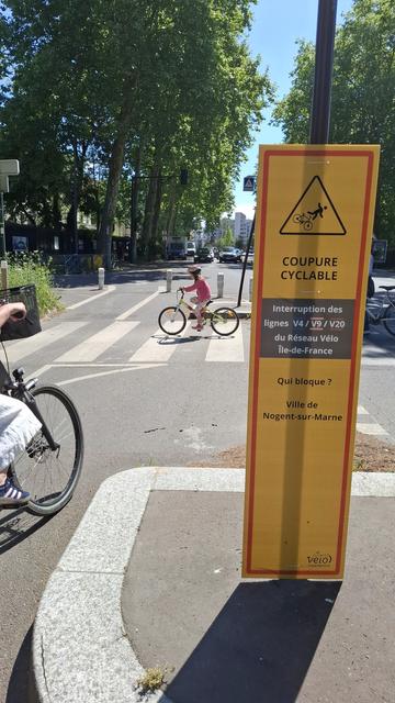 Fixé en bas d'un panneau de signalisation, un affichage où l'on peut lire que la coupure cyclable est due à l'inaction de la ville de Nogent Sur Marne. 

Le panneau est entouré de cyclistes