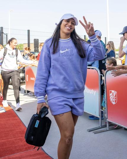 Zaneratto smiling at the camera as she arrives at the stadium, holding up a peace sign