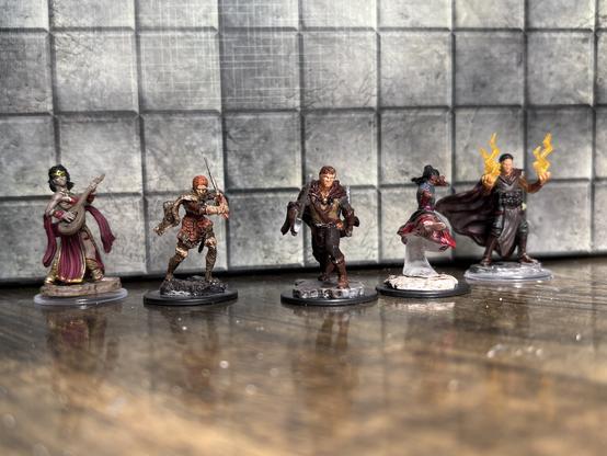 5 hero minis, all human. A female bard struming a lute, a female barbarian charging into battle with a sword, a male ranger charging with two swords, a monk performing a flying kick, and a male sorcerer with flames rising from his hands.