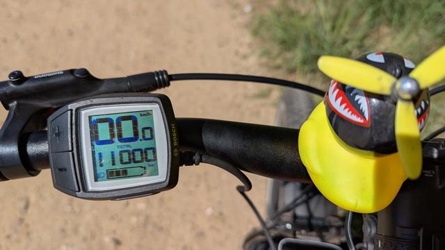 Lenker eines Fahrrads, das Fahrrad-Display zeigt 11000 km an. 
Rechts neben dem Display ist eine gelbe Propelller-Ente.