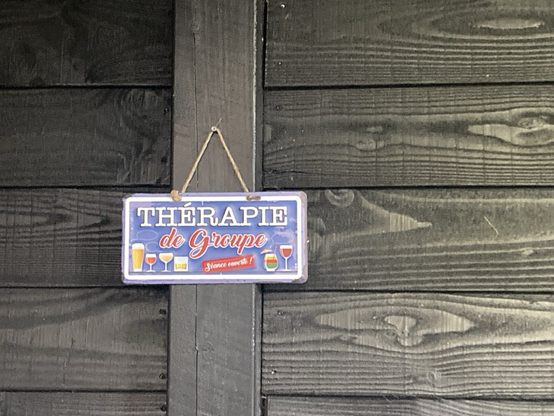 Bordje met Thérapie de Groupe. Séance ouverte. Met daaromheen glaasjes wijn en bier.