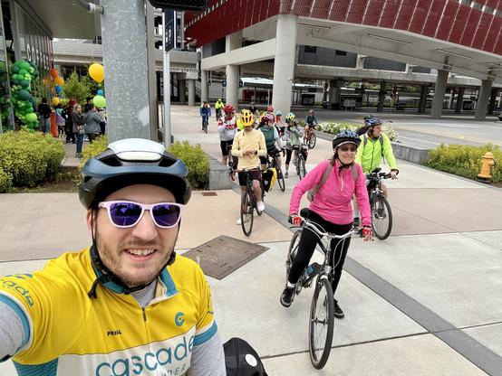 Selfie in my bright yellow Cascade Bicycle Club ride leader jersey in front of cyclists leaving Redmond Technology Station