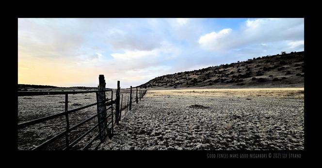 A fence runs across a natural pasture to meet the base of a hill on the horizon in western New Mexico just after sunset.