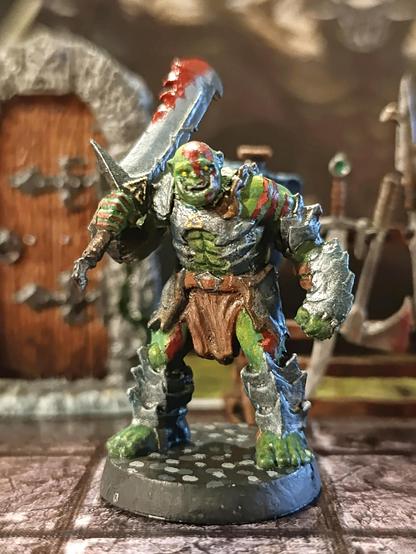 Miniatura de orco con la espada ensangrentada y expresión feroz.