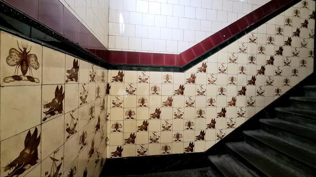 Decorative tiles featuring bees, the head of a wild boar and a galley.