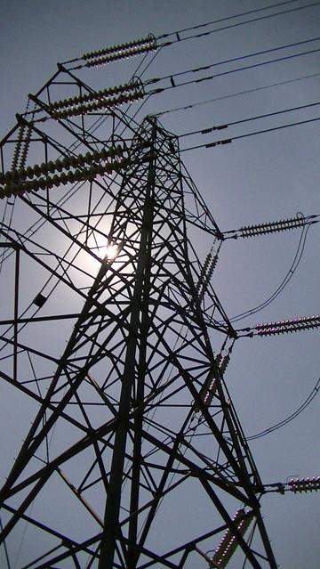Electricity pylon with the sun behind it.