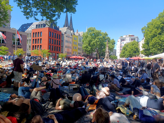 Hunderte Menschen liegen und sitzen auf dem Altermarkt, im Hintergrund ragen die Domspitzen über die Häuser der Kölner Altstadt