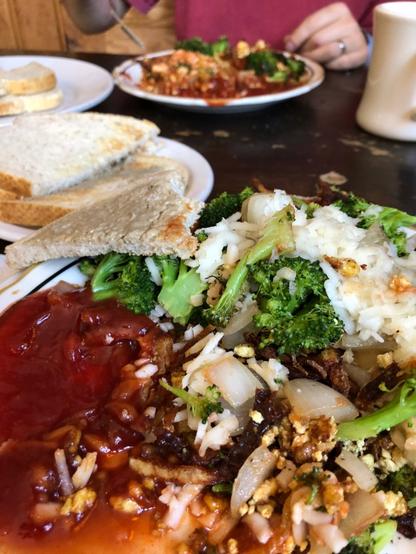 super green earth breakfast plate tofu broccoli onion vegan cheese hash brown potatoes and toast with some ketchup on the side