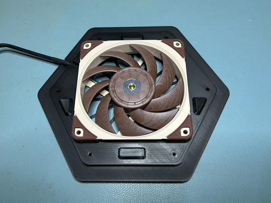 The bottom hexagonal surround is on the workbench.  The fan is installed into it, and the fan's cord runs through a slot near the back.