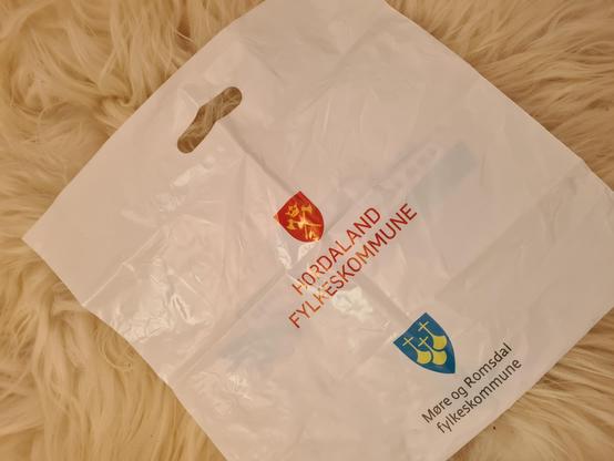 Den andre sida av Epos-posen. Midt på posen fylkesvåpenet til gamle Hordaland fylkeskommune, og nedst fylkesvåpenet til Møre og Romsdal fylkeskommune. Hordaland ropar med store bokstavar, Møre og Romsdal kviskrar.