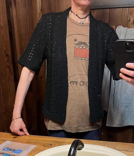 Selfie of me in my bathroom mirror trying on the black lace cardigan that I made for my mother. My Domo shirt is visible. Sleeves on the sweater come to right above the elbow.