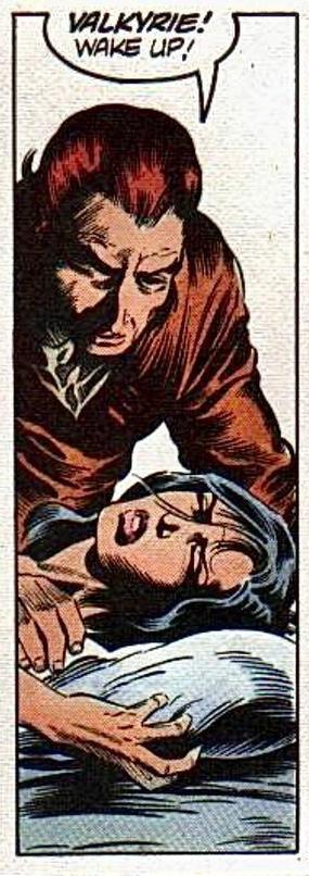 A man leans over a woman asleep in a bed. Her eyes are tightly closed. She’s clearly distressed, one hand grasps the side of a pillow tightly. The man shouts “VALKYRIE! Wake up!“