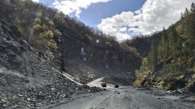 Bergstraße mit querenden Bach und heruntergefallenem Fels