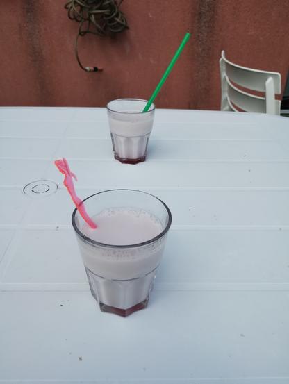 Deux verres de lait grenadine sur une table de jardin blanche