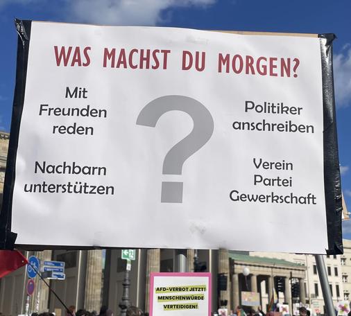 Auf dem Schild steht 'was machst du morgen? Mit Freunden reden, 
Politiker anschreiben,
Nachbarn unterstützen,
Verein Partei Gewerkschaft