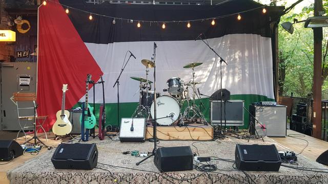 Photograph of an empty stage, rigged and ready, with large Palestine flag. Real photographer: me.