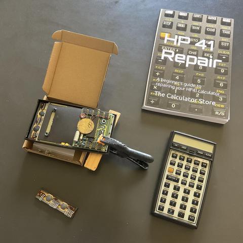 A cannibalized HP-41 calculator next to a working model and a repair book.