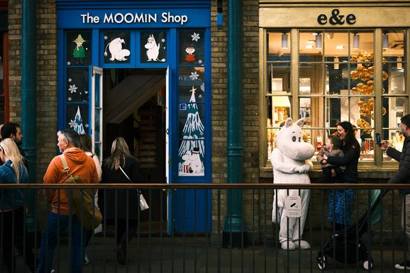 In Covent Garden Market, to the right of the Moomin shop, a small boy, held up by his mother, looks happily at someone dressed as Moomin.