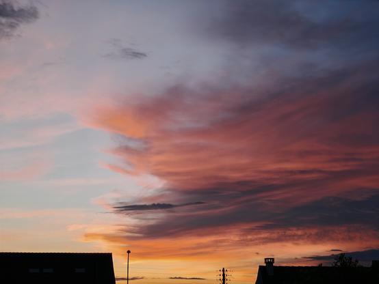 Un beau ciel nuageux au soleil couchant, au-dessus de quelques maisons voisines