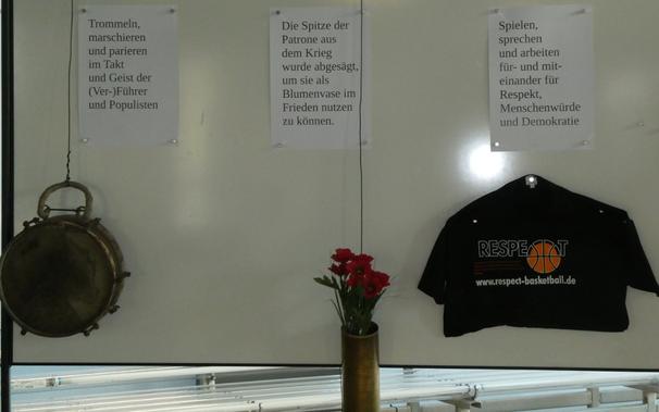 "Trommeln, Marschieren und parieren  im Takt und Geist der (Ver-)Führer und Populisten"
(Darunter: Eine Trommel der Hitlerjugend)

"Die Spitze der Patrone aus dem Krieg wurde abgesägt, um sie als Blumenvase im Frieden nutzen zu können."
(Darunter: Eine Mörserpatrone mit Blumen.)

"Spielen, sprechen und arbeiten für- u nd miteinander für Respekt, Menschenwürde und Demokratie"
(Darunter: Ein T-Shirt mit dem Aufdruck RESPEKT.)